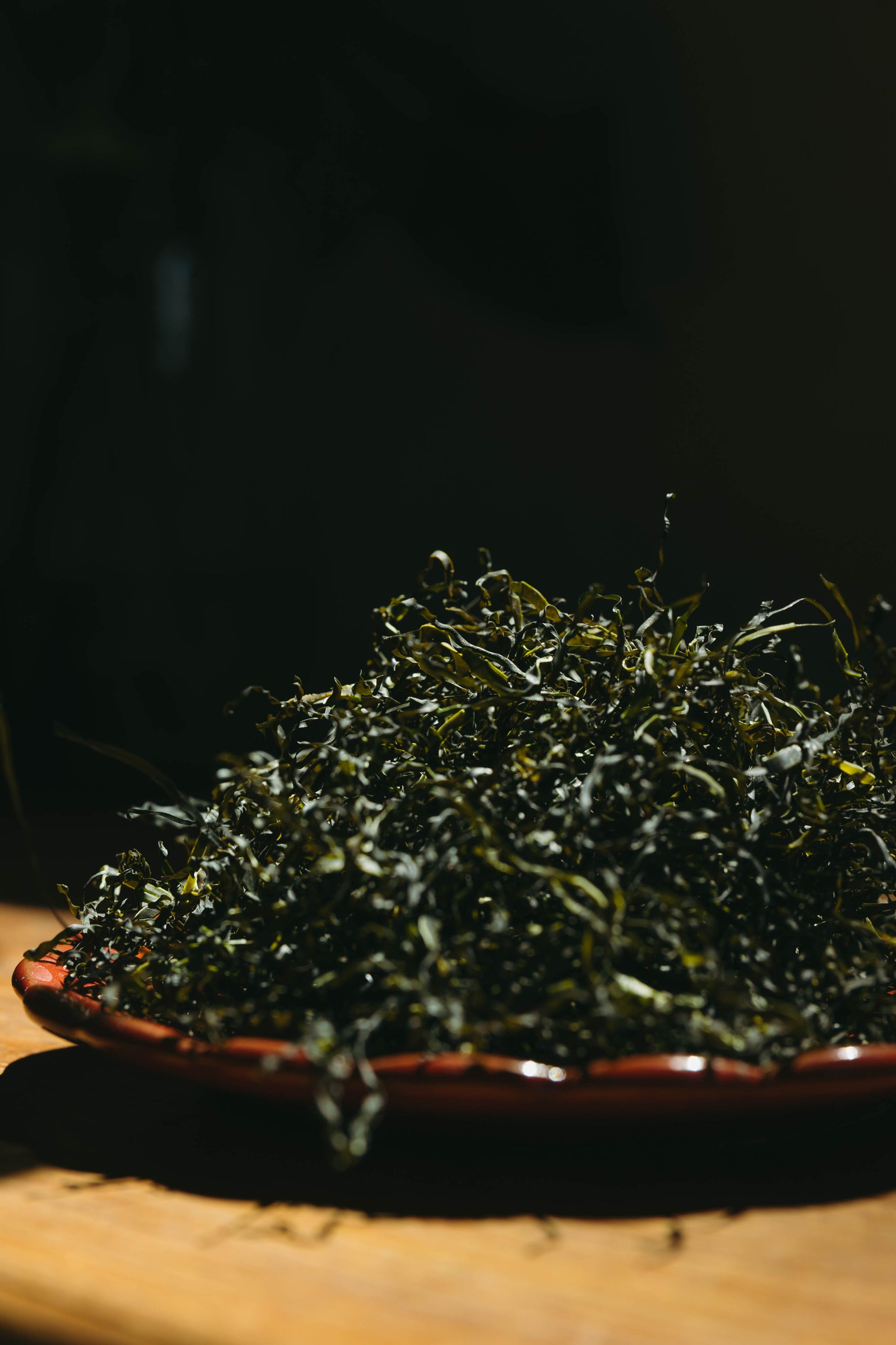 Dried Wakami seaweed on a wooden plate with a dark background