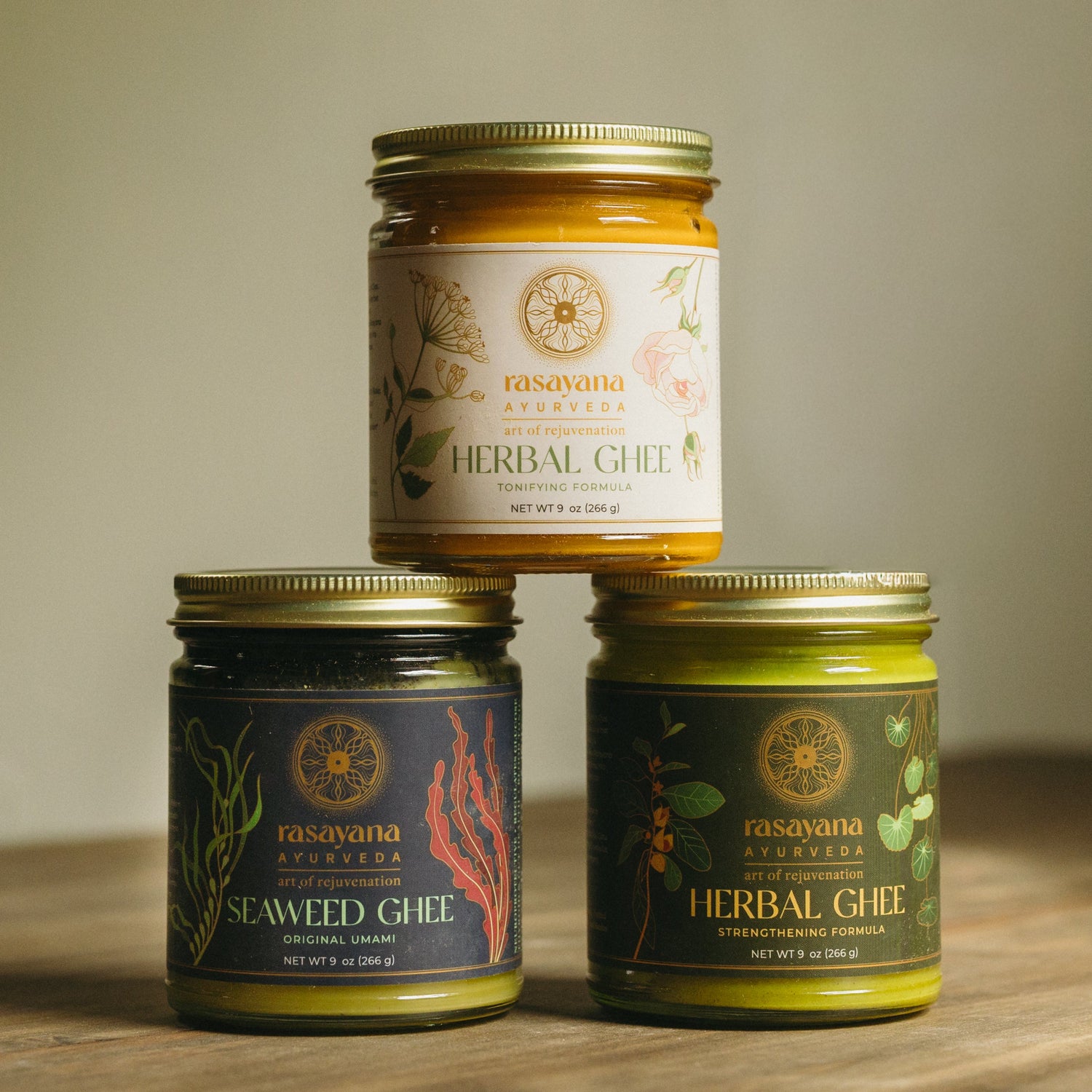 Three jars of herbal + seaweed ghee stacked on top of one another.