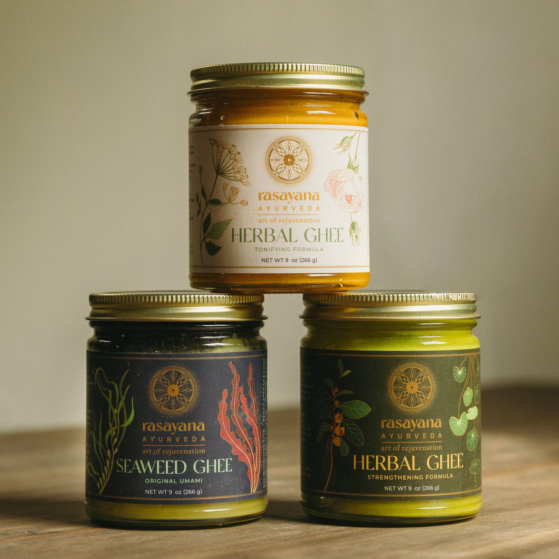 Three jars of herbal + seaweed ghee stacked on top of one another.